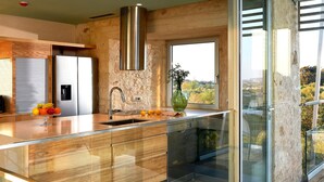 A modern kitchen with a large island, stainless steel appliances, and a view of the outdoors. - Olives and Thyme Retreat (Chania)