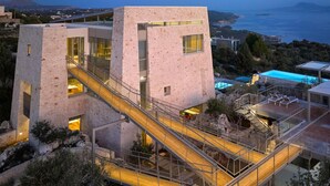 A modern building with a central staircase, a pool, and a view of the sea. - Olives and Thyme Retreat (Chania)