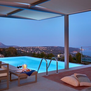 A modern infinity pool with a clear view of a distant cityscape at dusk. - Olives and Thyme Retreat (Chania)