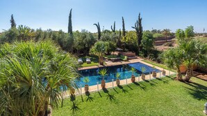 A swimming pool surrounded by lush greenery and tall trees. - Luxury villa with swimming pool, not overlooked. (Marrakech)