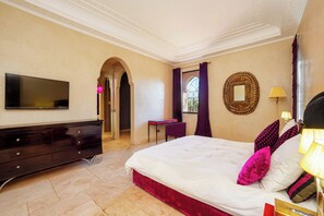 A hotel room with a bed, a television, a dresser, a desk, and a mirror.