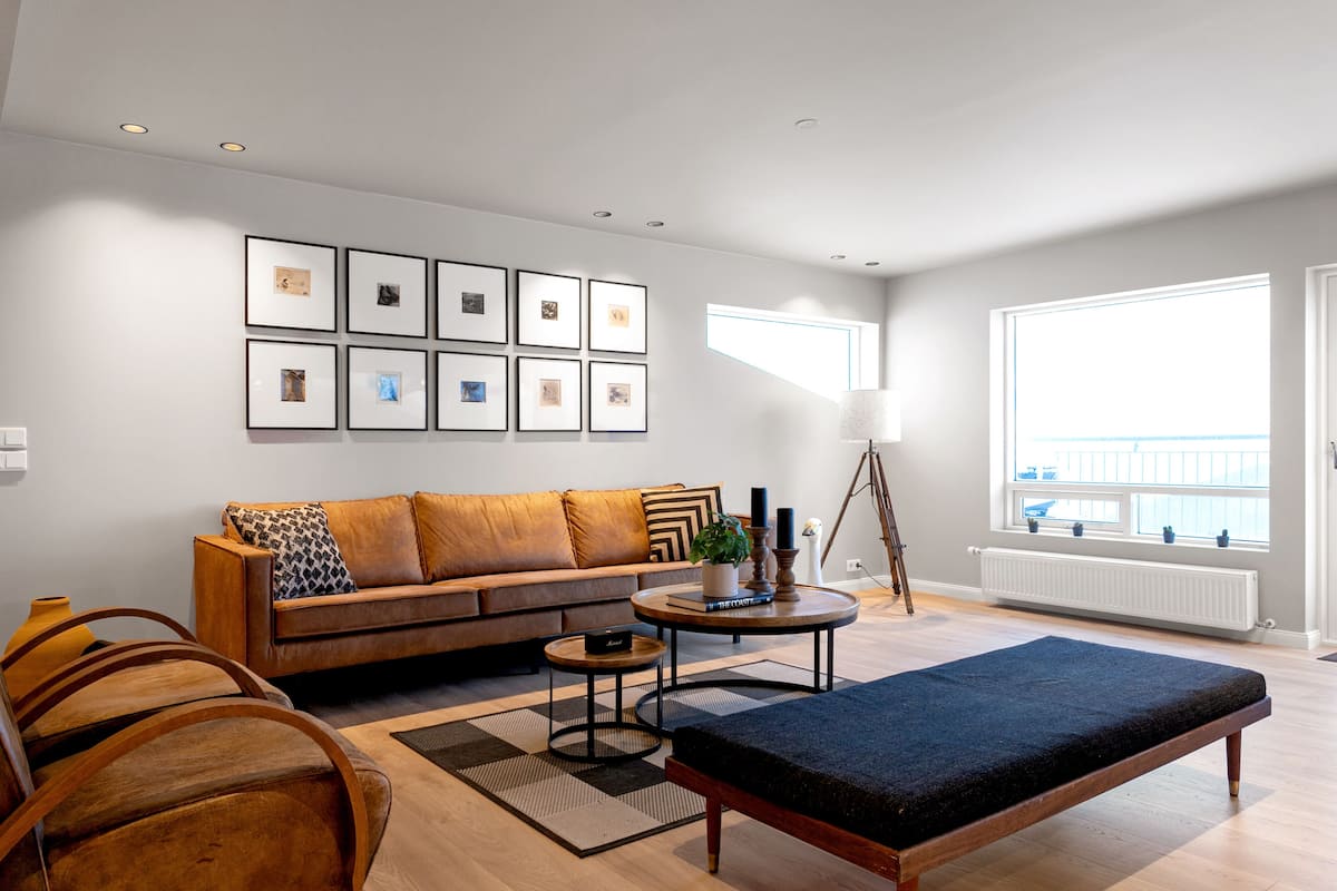 A modern living room with a sofa, a coffee table, a bench, and framed pictures on the wall.