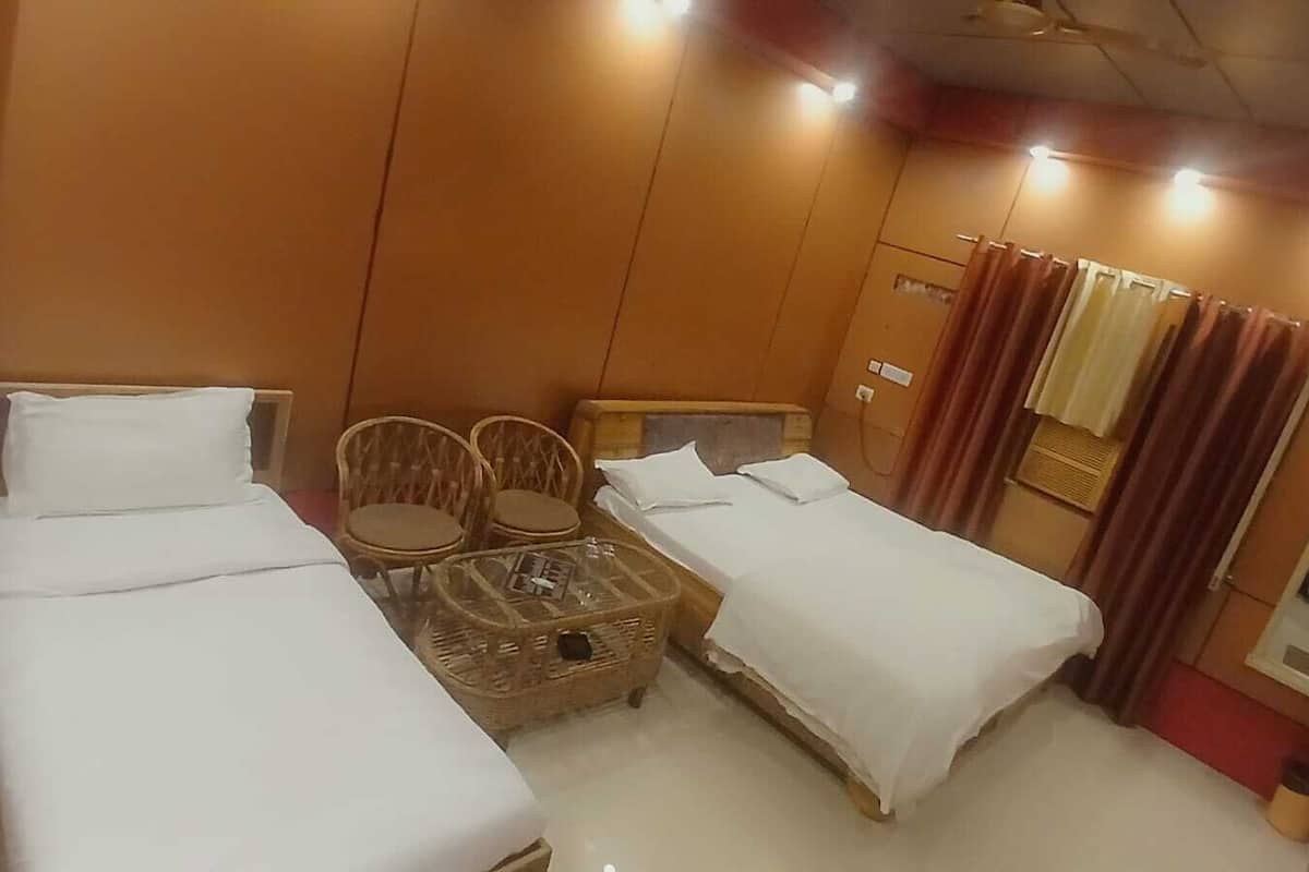 Une chambre d’hôtel avec deux lits simples, une petite table avec des chaises et une fenêtre avec des rideaux.