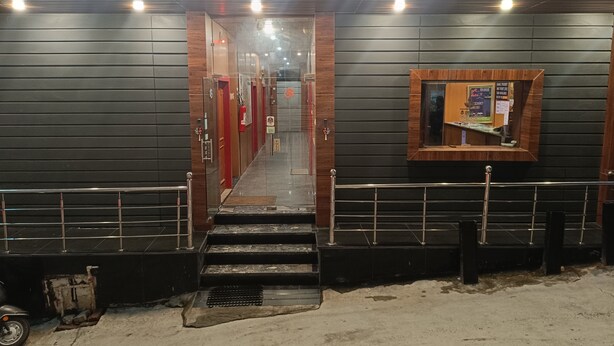 The entrance to Shiv Ganga Hotel with a sign above the doors, a reception desk, and a staircase leading inside. - Shiv Ganga Hotel (Narendranagar)