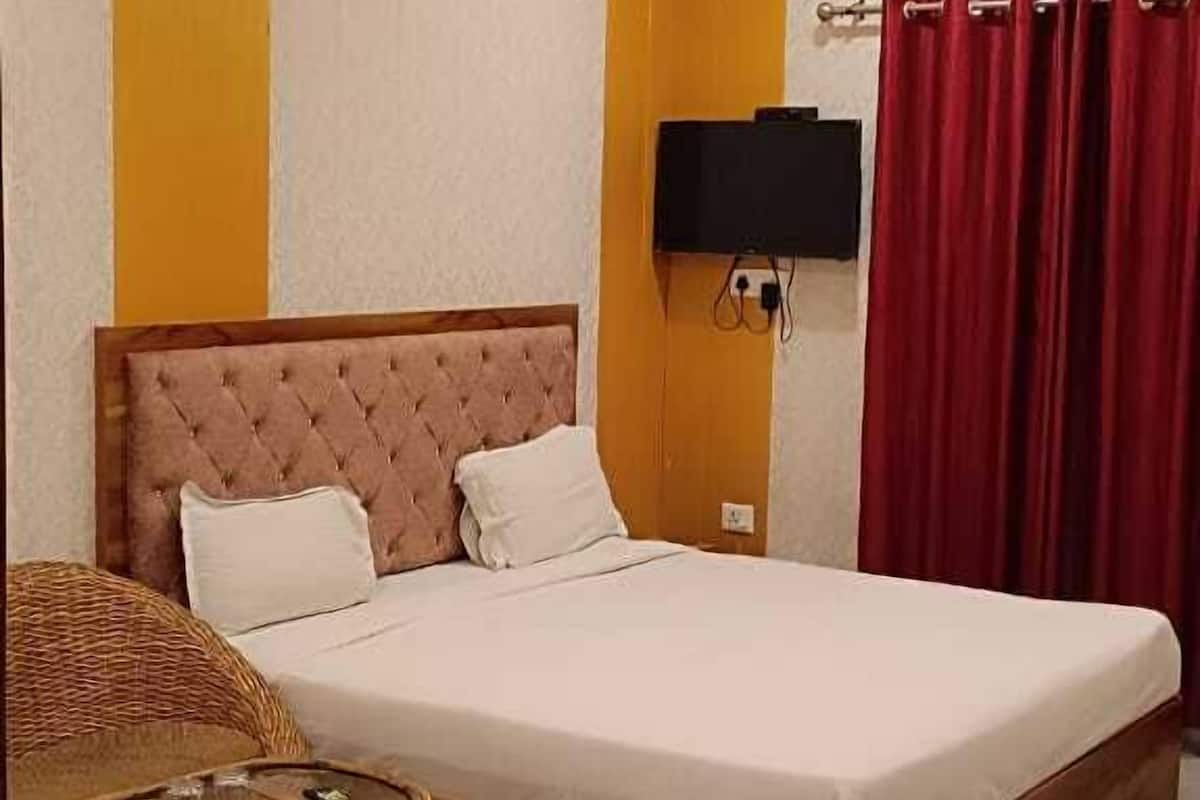 Une chambre d’hôtel avec un grand lit, une télévision, un ventilateur de plafond et un rideau rouge.