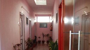 A corridor with potted plants, a glass door, and a ceiling light. - Shiv Ganga Hotel (Narendranagar)