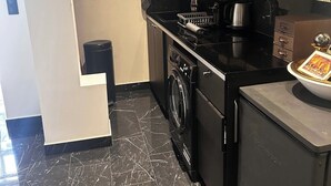 A modern kitchen with a black countertop, a built-in oven, a microwave, and a washing machine. - Charment T2 Champ-Elysée    (Paris)