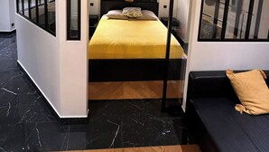 A modern bedroom with a bed, a sofa, and a unique black and white headboard design. - Charment T2 Champ-Elysée    (Paris)