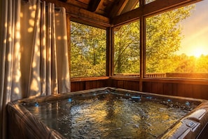 Un jacuzzi con vistas a árboles a través de amplios ventanales.
