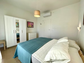 Une chambre à coucher comprenant un lit, une armoire, une commode et un appareil de climatisation.