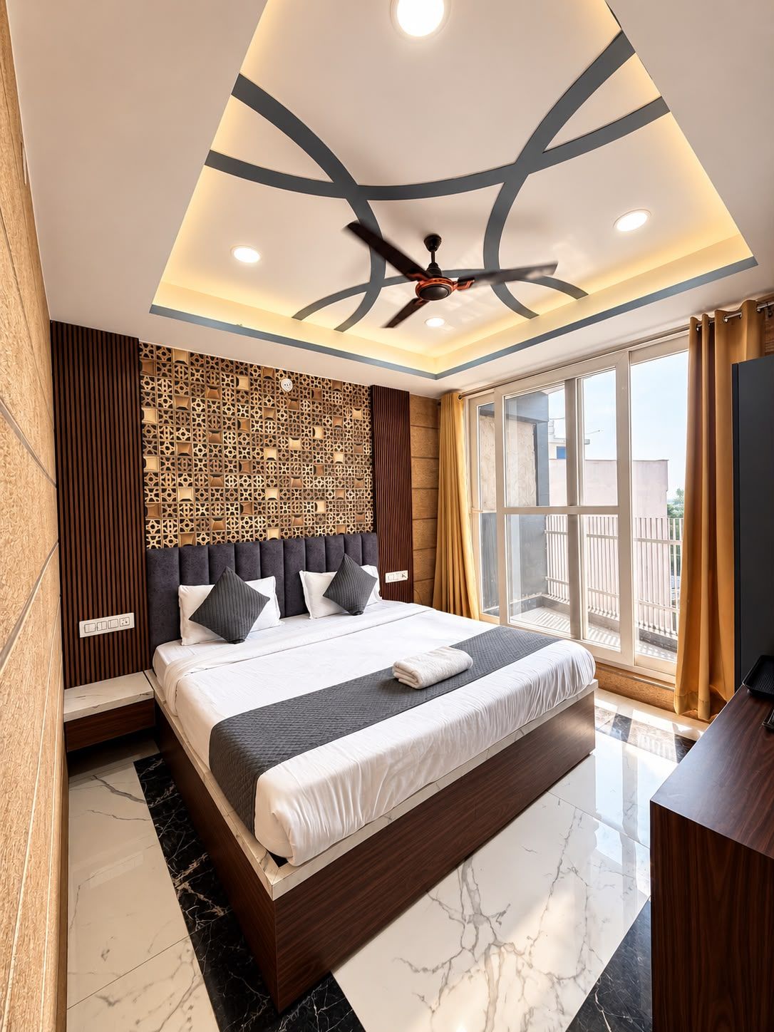 Una habitación de hotel moderna con una cama grande, un ventilador de techo y vistas al exterior a través de un amplio ventanal.