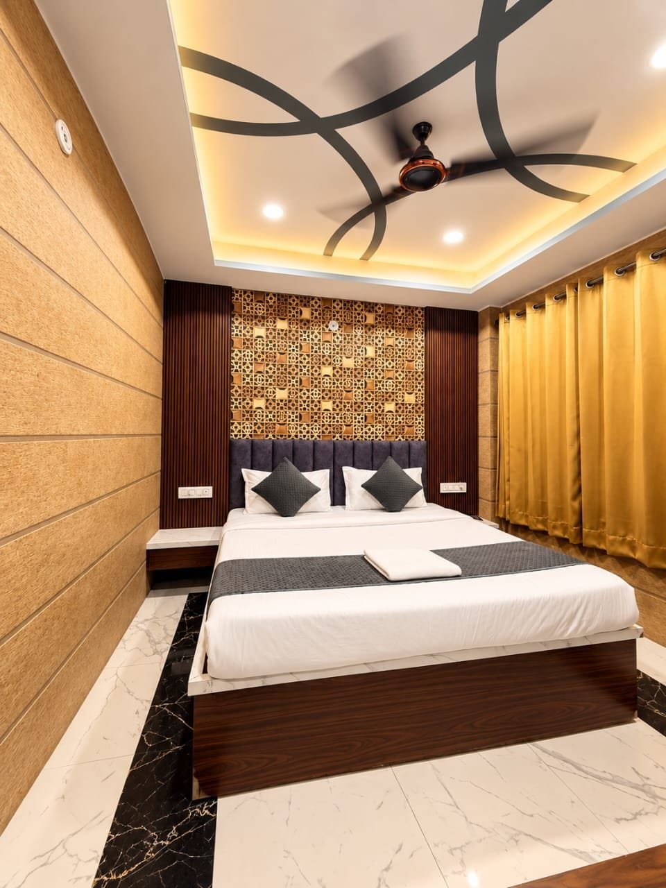 Una habitación de hotel moderna con una cama grande, un ventilador de techo y un panel decorativo en la pared.