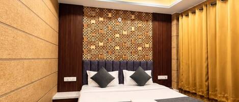 Una habitación de hotel moderna con una cama grande, un ventilador de techo y un panel decorativo en la pared.