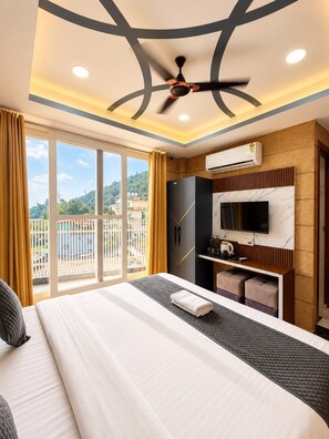 Une chambre d’hôtel équipée d’un lit, d’une télévision, d’un système de climatisation et d’un balcon avec vue.