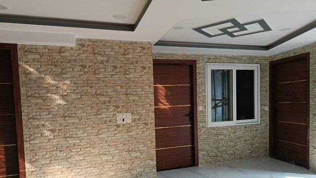 A room with a brick wall, two wooden doors, a window, and a marble floor. - Hotel Asha Delight (Narendranagar)