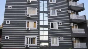 A multi-story building with a modern architectural design, featuring a mix of balconies and windows. - Hotel Asha Delight (Narendranagar)