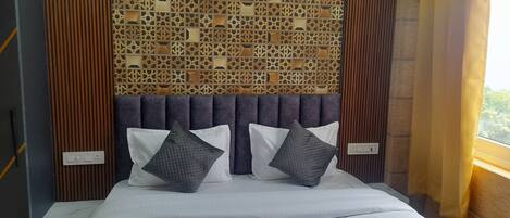 A neatly made bed with white linens and two pillows, a wooden headboard, and a decorative wall panel.