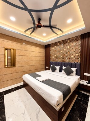 A modern hotel room with a large bed, a ceiling fan, and a decorative wall panel. - Hotel Asha Delight (Narendranagar)