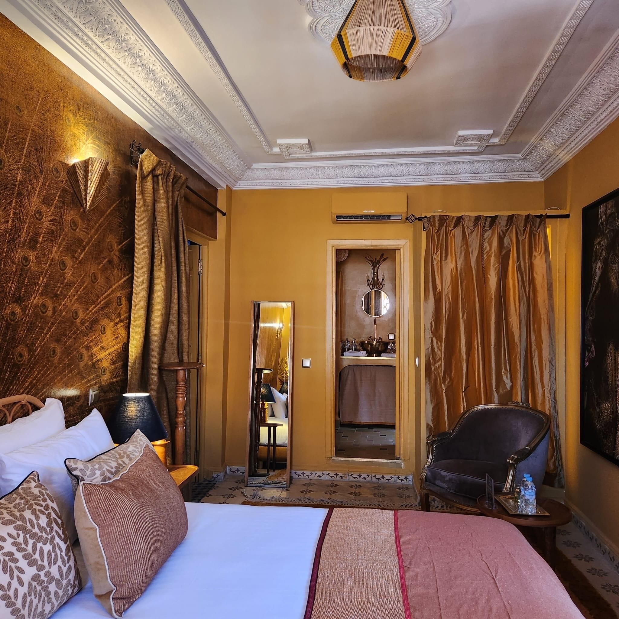 Una habitación de hotel con una cama grande, una silla, un espejo y un armario.