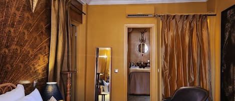 Una habitación de hotel con una cama grande, una silla, un espejo y un armario.