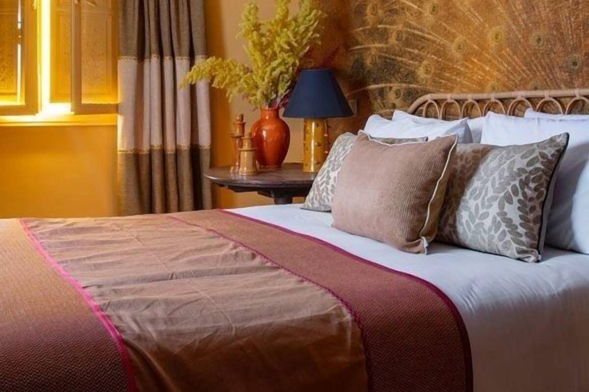 Una habitación de hotel con una cama, una mesita de noche, una lámpara y un adorno en la pared.