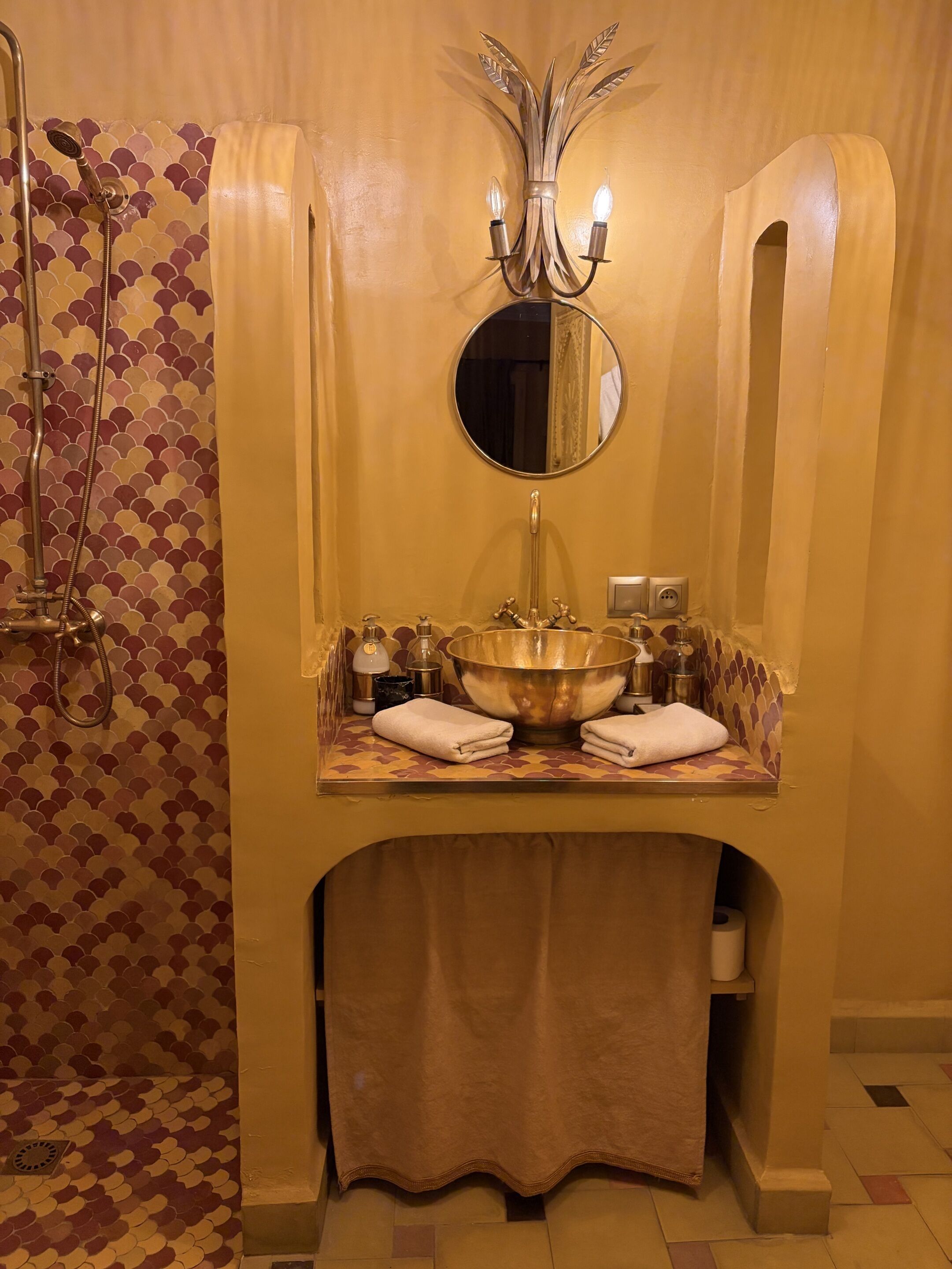 Une salle de bain avec un grand lavabo, une douche, un miroir et un porte-serviettes.