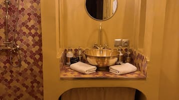 Une salle de bain avec un grand lavabo, une douche, un miroir et un porte-serviettes.