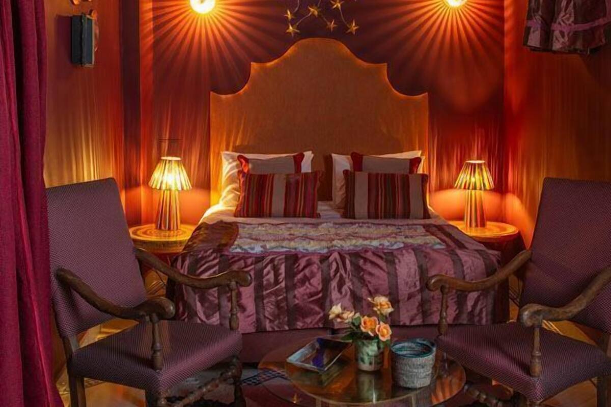 Una habitación con una cama grande, dos lámparas de noche y un candelabro colgante.