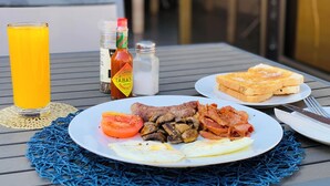 A breakfast plate with eggs, bacon, mushrooms, and tomato slices, accompanied by toast and a glass of orange juice. - Ascentia Guest House (Jwaneng)