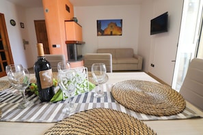 A dining table set with wine glasses, a bottle of wine, and placemats. - Calipso's Home in Otranto (Otranto)