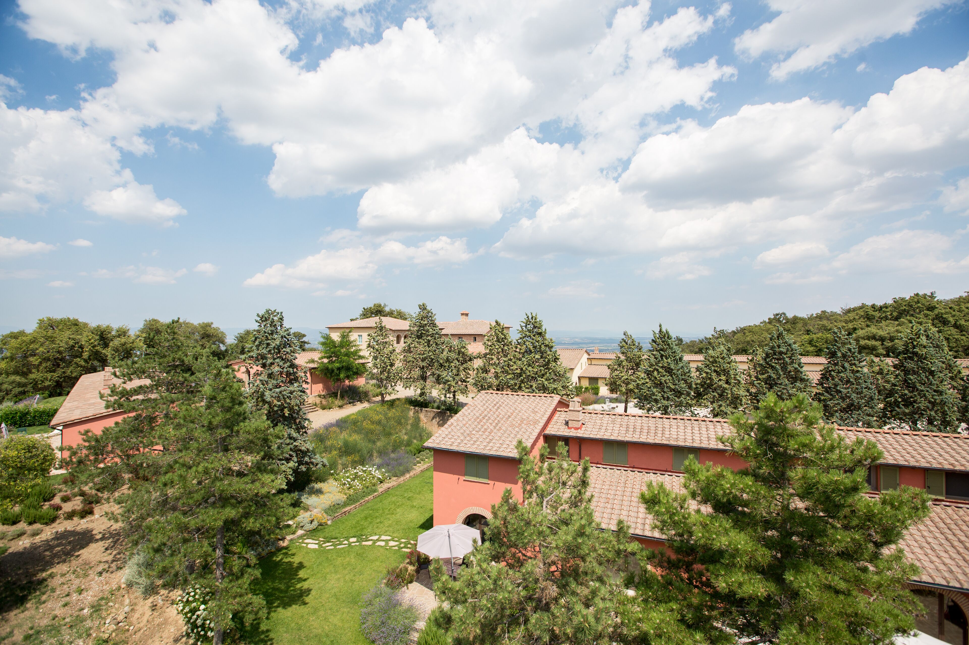 A residential area with multiple houses, each with a tiled roof and surrounded by greenery.