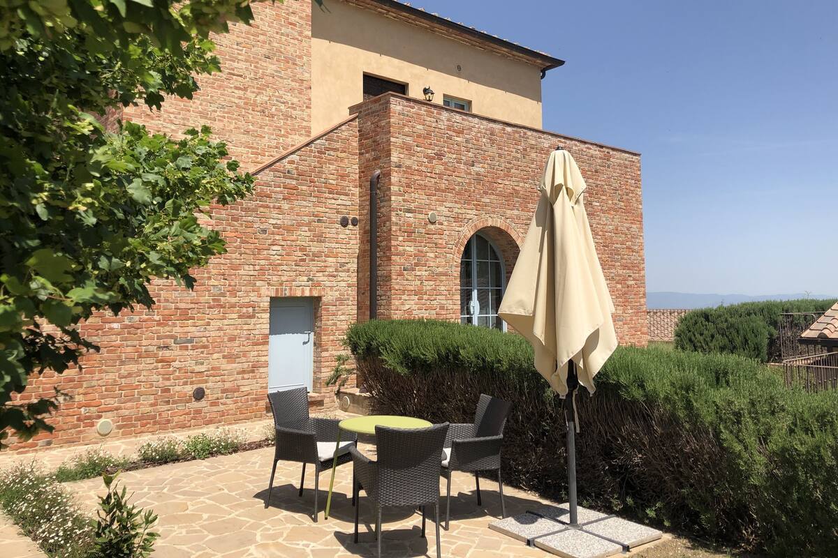 A brick building with a patio area featuring outdoor furniture and a large umbrella.