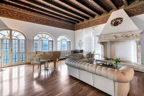 Une pièce spacieuse avec un grand piano, un grand canapé beige et une cheminée.