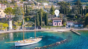 A coastal town with a clear harbor, a sailboat docked, and a prominent building with a red roof. - Villa Schlosser Lake Front & Private Pool (Malcesine)