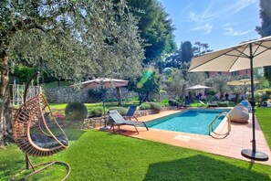 Un patio trasero con piscina, una hamaca y dos sillones de descanso.