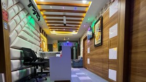 Zona de recepción de un hotel con mostrador de check-in, área de descanso y un diseño moderno en el techo.