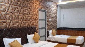 Habitación de hotel con dos camas, un diseño moderno geométrico en la pared y un área de baño separada.