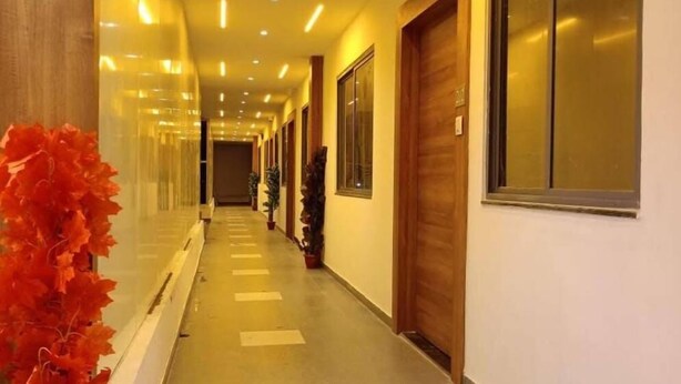 Un pasillo largo, bien iluminado, con suelo de baldosas, puertas de madera y ventanas amplias a un lado.