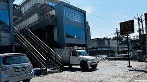 Un hotel con una escalera que conduce a la entrada, un camión blanco estacionado y un letrero que indica que el hotel está en el segundo piso.