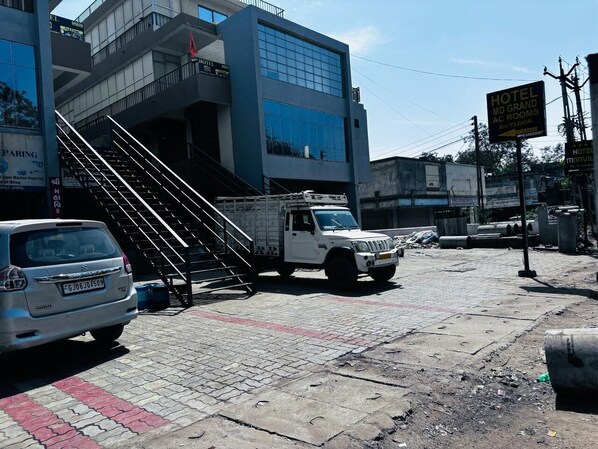 Un hotel con una escalera que conduce a la entrada, un camión blanco estacionado y un letrero que indica que el hotel está en el segundo piso.