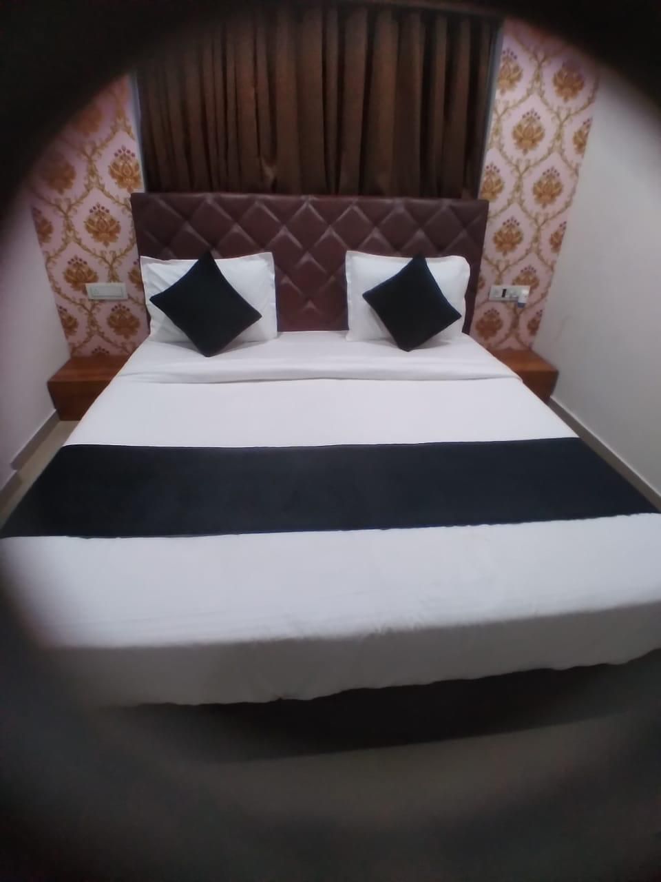 A bed with a headboard, two pillows, and a black bedspread.