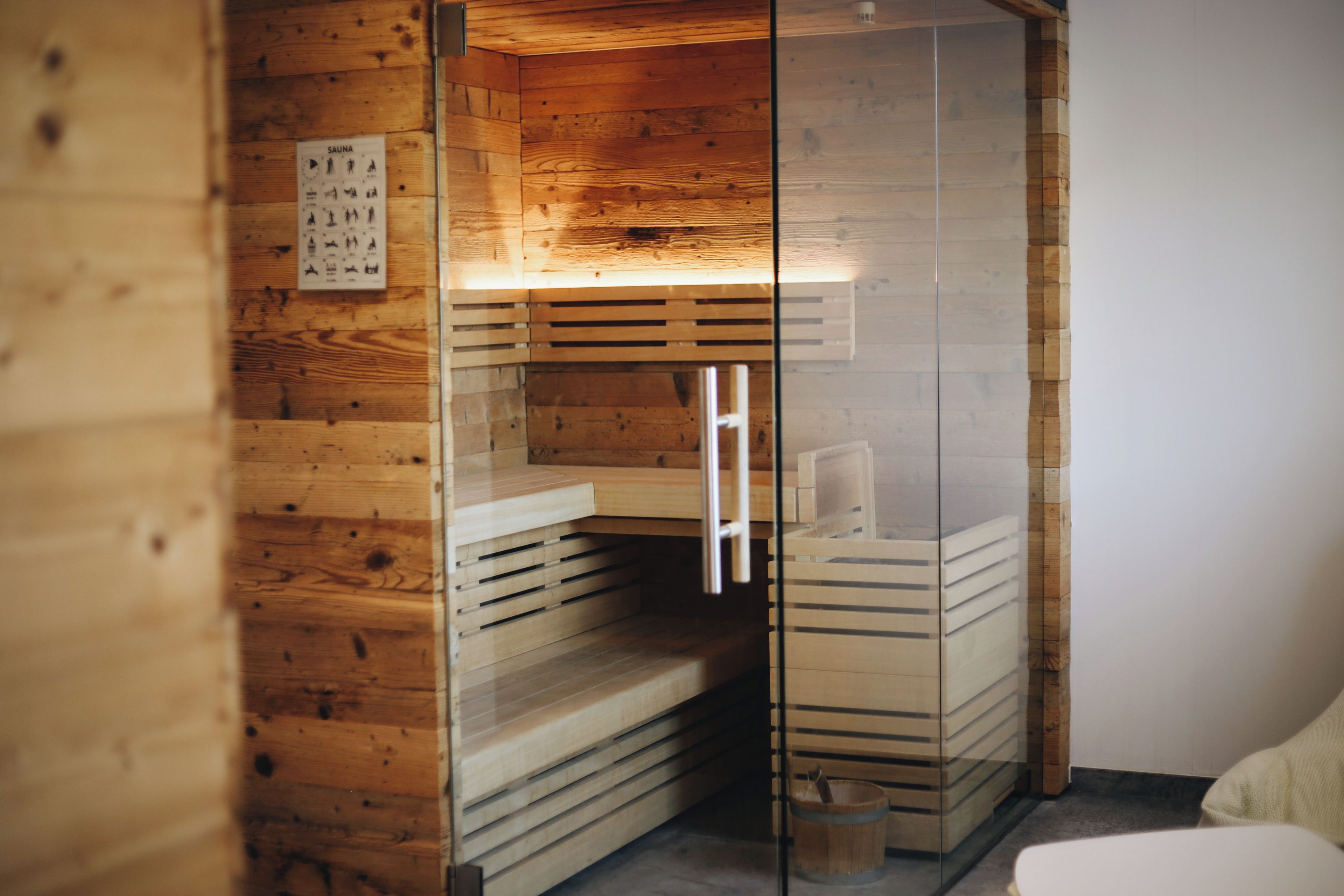 Een sauna met houten wanden, een glazen wand en een houten bank.