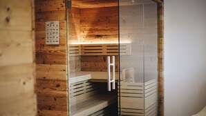 Una sala de sauna con paredes de madera, una pared de vidrio y un banco de madera.