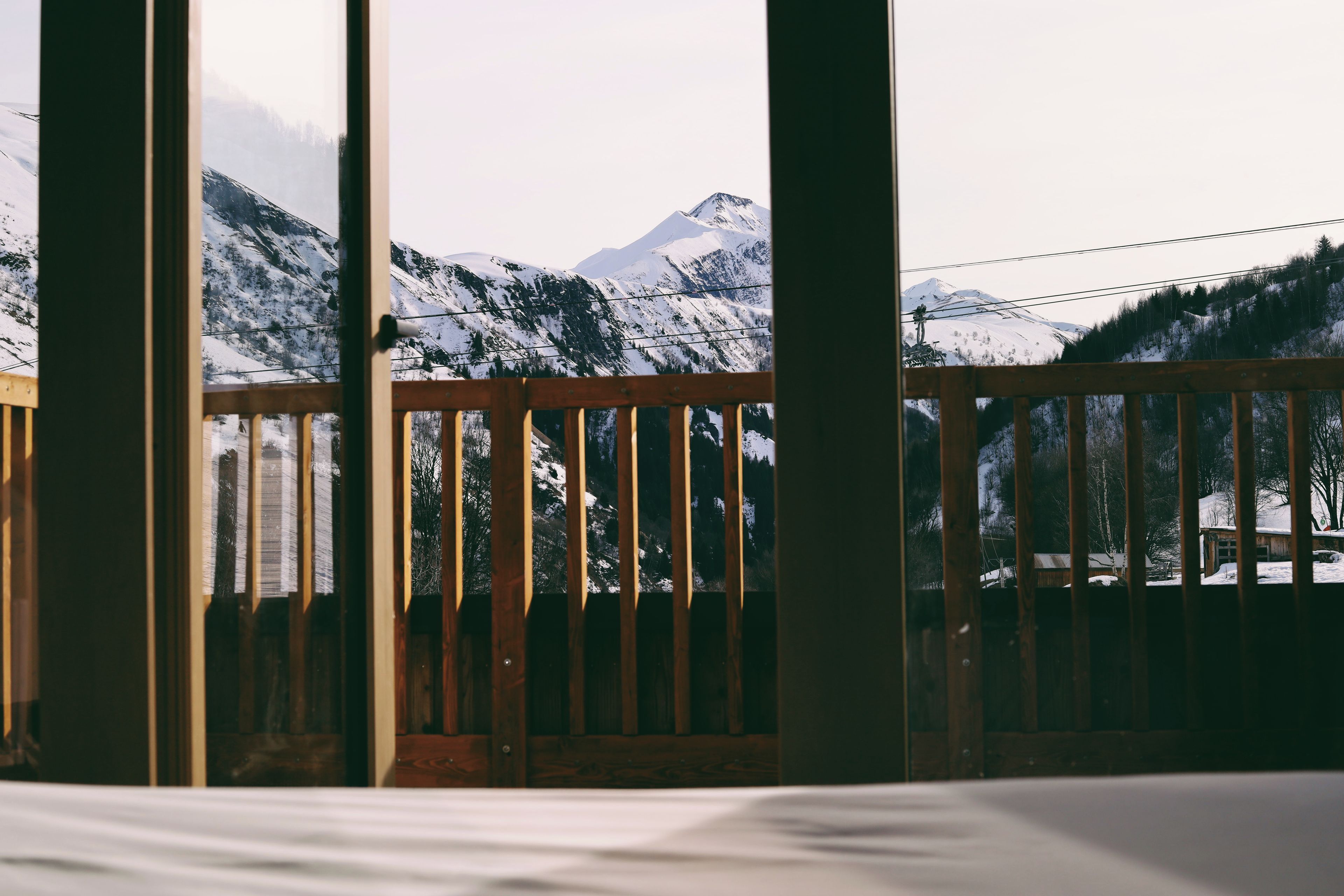 Een houten balkon met uitzicht op besneeuwde bergen.