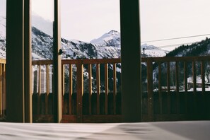 A wooden balcony with a view of snow-covered mountains.