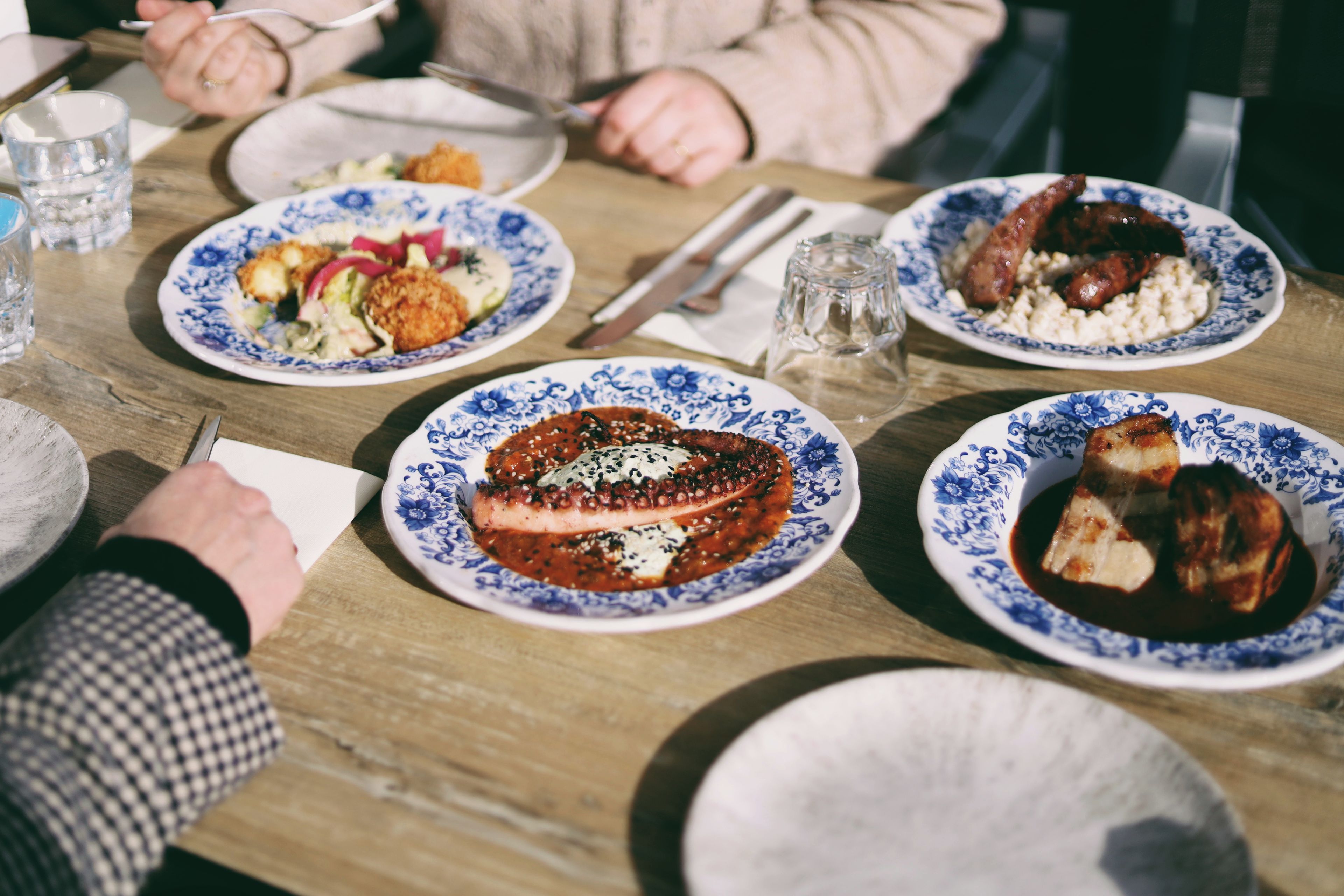 A dining table with plates of food, utensils, and a glass of water.