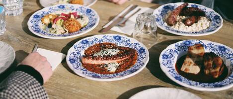 A dining table with plates of food, utensils, and a glass of water.