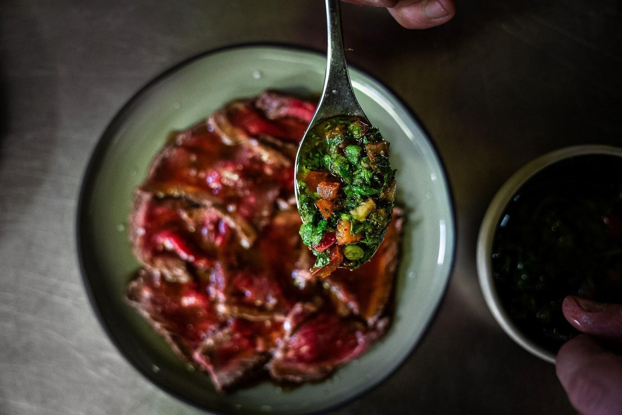 A spoonful of food being held over a plate.