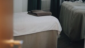 Een hotelkamer met twee bedden, een radiator, een lamp en een muur met een bergmotief.