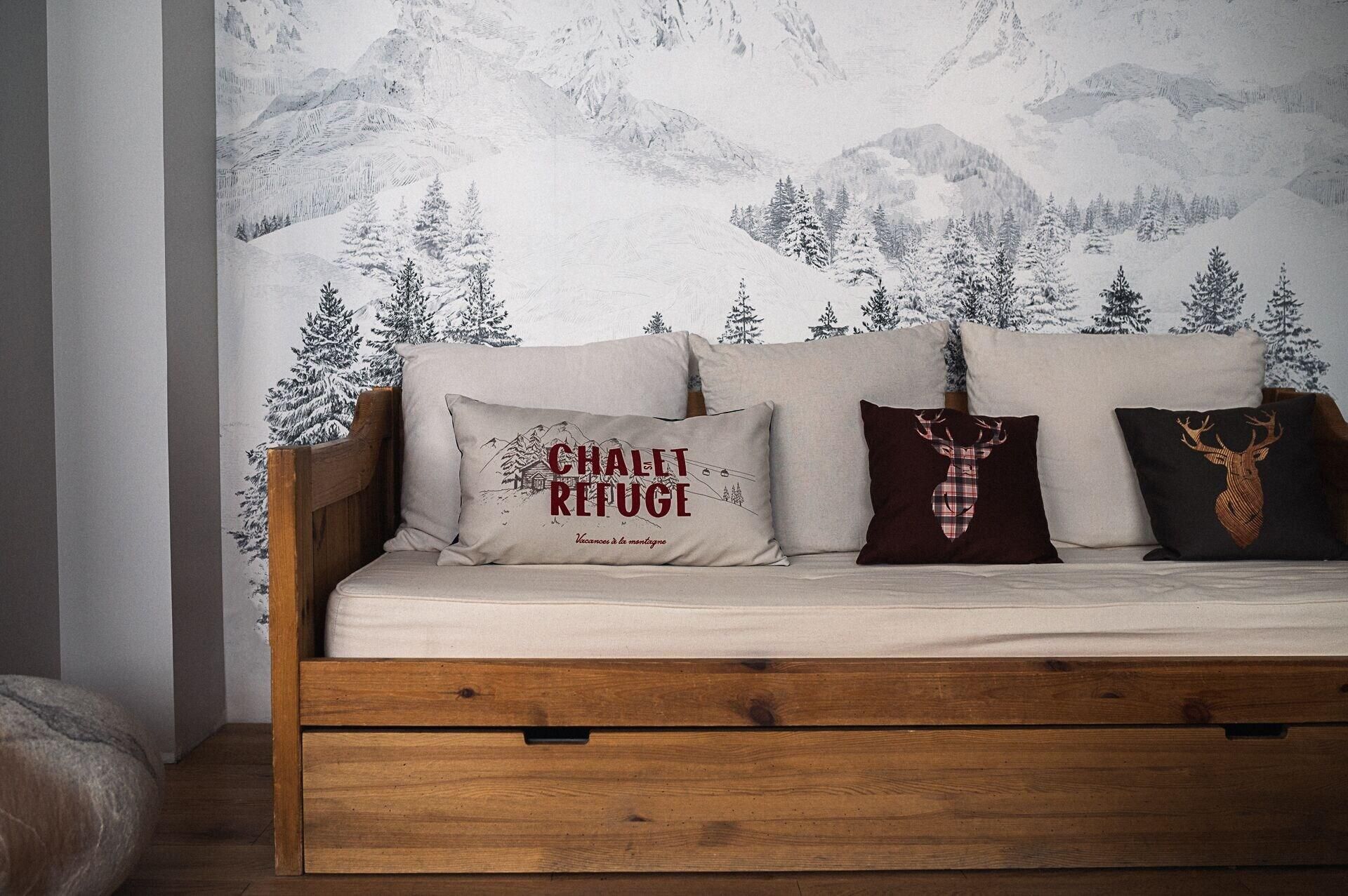 Una cama de madera con tres almohadas, cada una con diseños distintos.